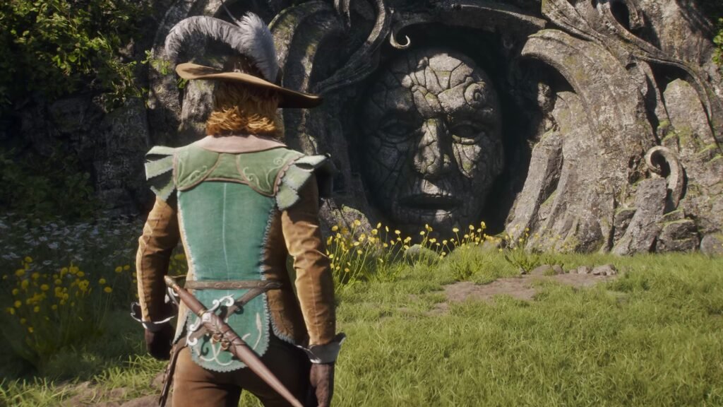 Fable - Official Release Date Trailer _ Xbox Games Showcase 2026 1-36 screenshot - GamersPack ישראל Adventurer in green medieval armor and hat stands before a carved stone face in a rocky wall, with yellow flowers and grass in the foreground. Fable - Official Release Date Trailer _ Xbox Games Showcase 2026 1-36 screenshot