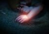 The Legend of Zelda: Ocarina of Time – הרימייק הוכרז רשמית Hands resting on a woven mat with a glowing Triforce-like triangle on the wrist in dim light