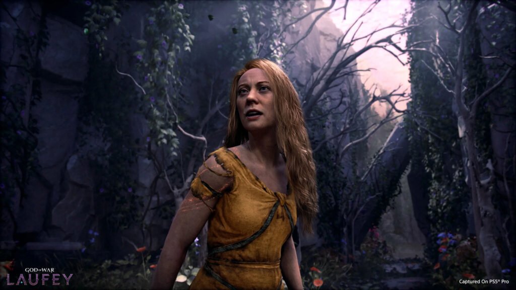 god of war laufey 4 - GamersPack ישראל Woman with long hair in a torn yellow tunic stands in a dark, vine-covered forest, looking upward intent. god of war laufey 4