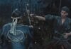 Two samurai duel at night as one man slashes with a sword, sparks flying and blood on their robes, a wooden fence behind them.
