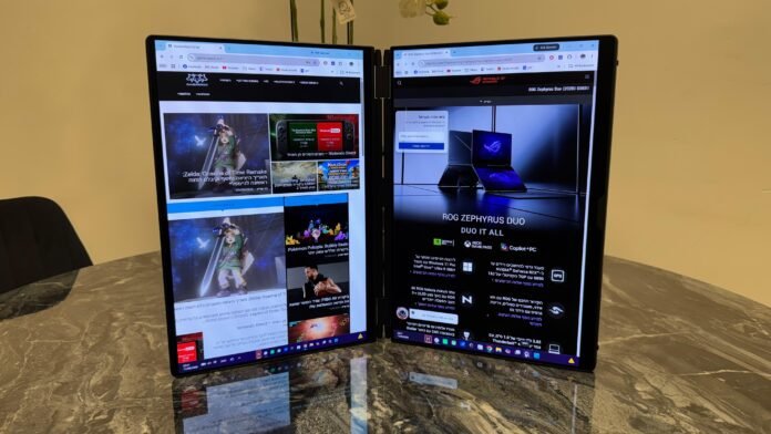 Two tall curved monitors on a marble table display Hebrew gaming sites, with Zelda news on the left and ROG Zephyrus Duo promo on the right, in an office.